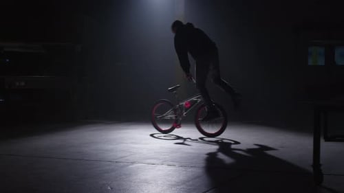 Bmx rider performing extreme stunts in dark urban warehouse filmed on red epic
