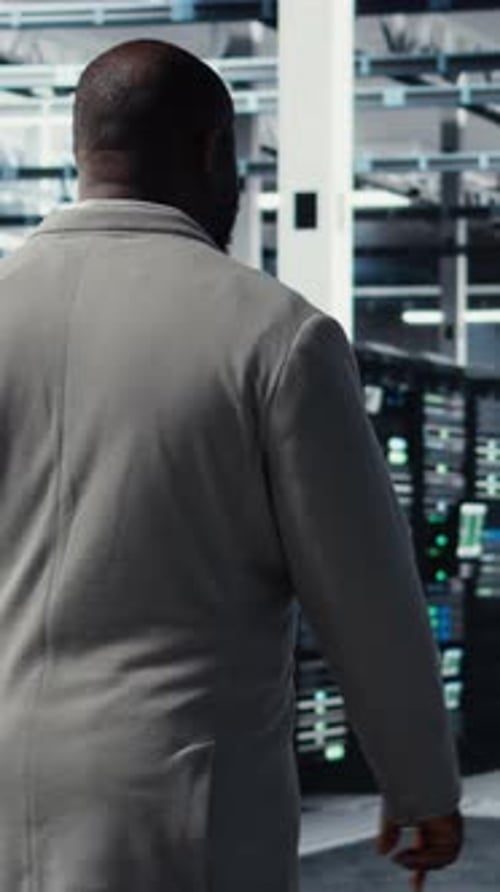 Vertical Video Engineer Walking in Server Farm Automating System Diagnostics