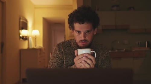Young Adult with Mug Sitting in Front of Computer
