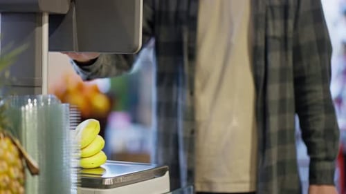 Close Up Supermarket Visitor Weighs Bananas Using Scales in Supermarket A Guy in a Plaid Shirt Uses