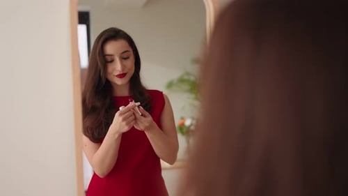 Woman Applies Lipstick in Front of Mirror