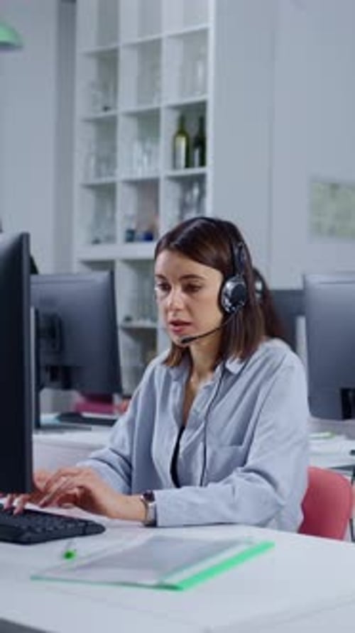 Focused Female Call Center Operator Wearing Headset Working on Computer in Modern Open Plan Office
