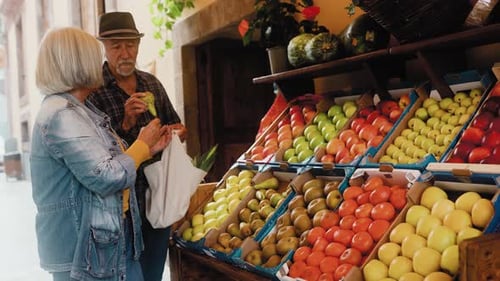 Happy senior couple buying fruits and vegetables at the market - Shopping food concept