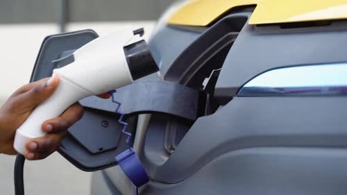 Unrecognizable Black Man Unplugs Charging Cable Electric Vehicle Green Energy Eco Friendly Fuel Male