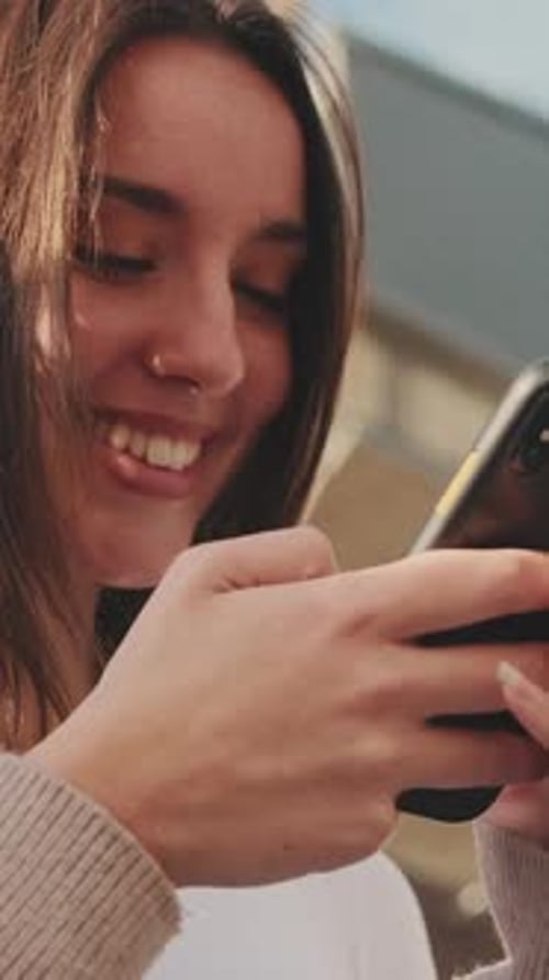 Woman Using Smartphone and Smiling Outdoors