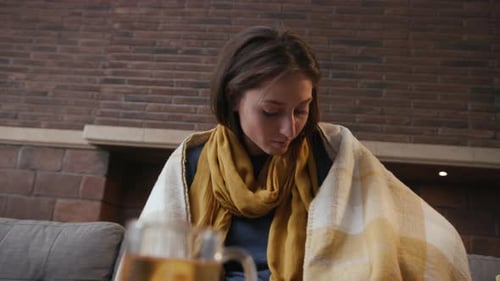Woman with Tea and Thermometer on Sofa