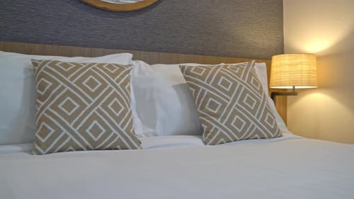 Comfortable Bed with Pillows and Bedside Lamp