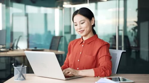 Happy young asian female employee finished work on laptop sitting at workplace in business office.