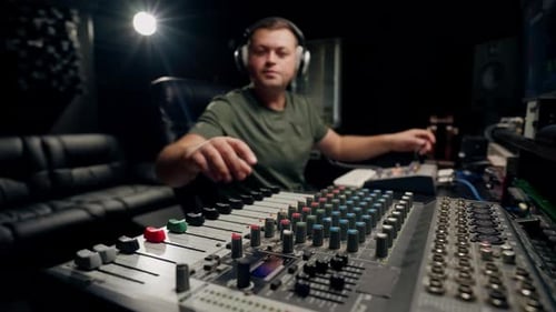 A close-up of a mixing console device used by a man working as professional sound engineer