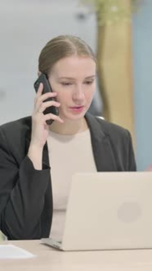 Businesswoman Talking on Mobile Phone at Desk