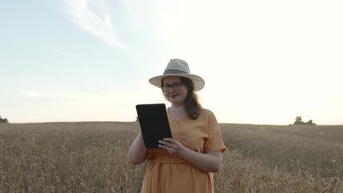 Positive Woman in Glasses Stands in Cereal Field and Used Tablet Slow Motion