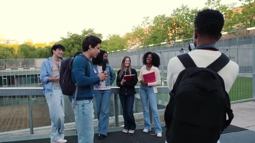 Young student vlogging with friends on a college campus bridge