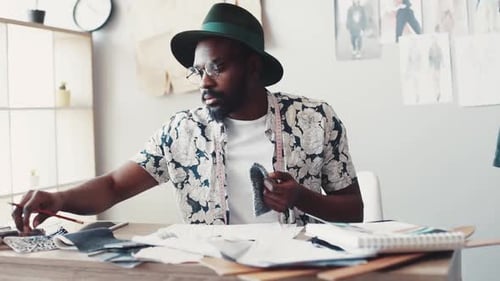 Fashion Designer at Desk Drawing and Selecting Fabrics