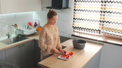 Young Woman Chopping Red Bell Pepper in Kitchen