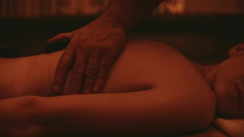 Man hands making massage on woman body in spa center with hot stones in slow motion