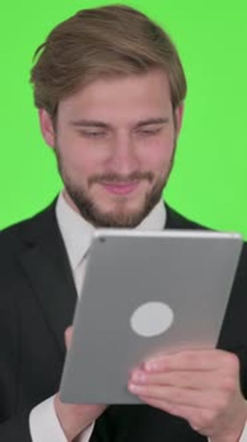Junger Geschäftsmann mit digitalem Tablet auf grünem Hintergrund, vertikales Video