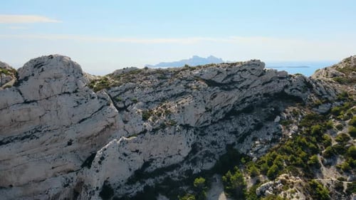 Drone view flying over a rocky cliff to reveal the shimmering sea off the coast of southern France