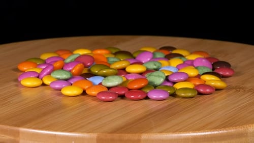 Colorful Candy Coated Chocolates on Rotating Wooden Surface