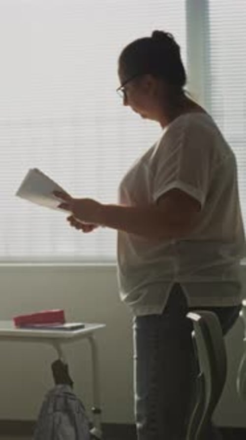 Female Teacher Preparing Space for Lesson or School Test in Classroom