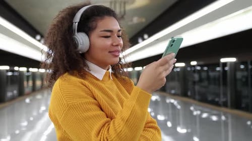 Slow Motion African Female Waits for a Train in the Subway Listen to Music with Headphones and Uses