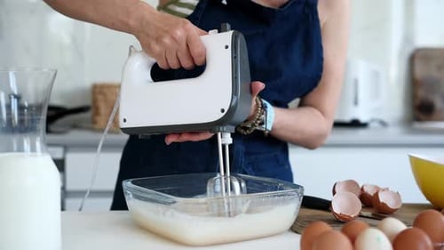 Woman Mixing Batter with Electric Mixer in Kitchen