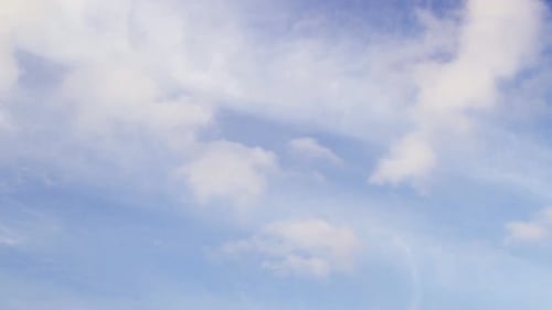 Weiße, flauschige Wolken wehen im Zeitraffer an einem schönen, sonnigen Tag an einem blauen Himmel
