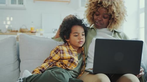 Woman and Child Watching Laptop Together on Sofa