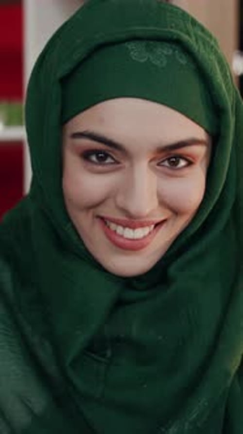 A Joyful and Smiling Woman Wearing a Beautiful Green Hijab Radiates Warmth and Happiness