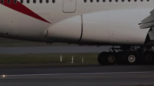 Plane taxies on runway, landing gear turning.