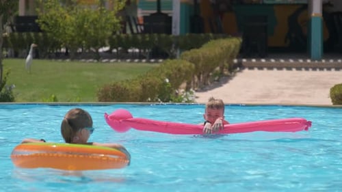 Happy Children Brother and Sister Playing on Inflatable Air Mattress in Swimming Pool on Sunny