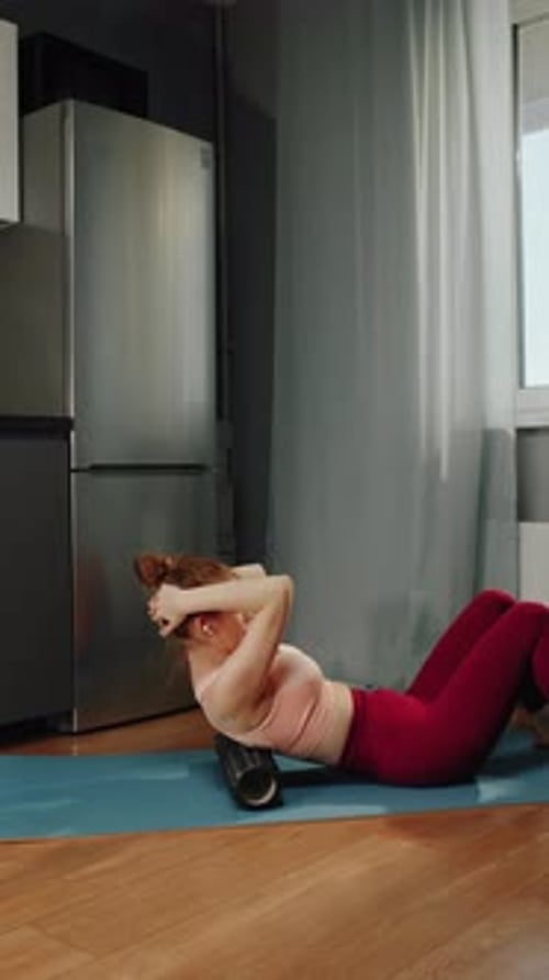 Woman Using Foam Roller on Back on Exercise Mat