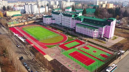 Green and red stadiums near the modern building. Modern outdoor fields for sports in the city