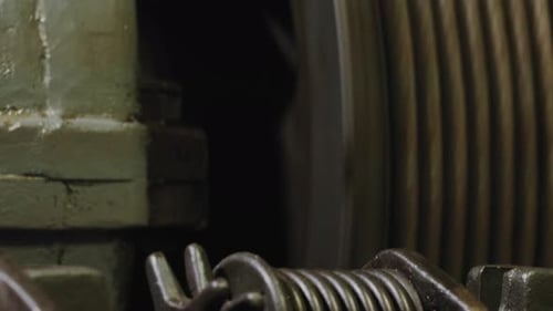 Close up shot of wheel spinning anti clockwise of a manual elevator in a dark background.