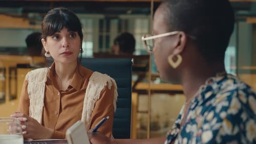Two Young Female Coworkers Having Discussion on Office Meeting