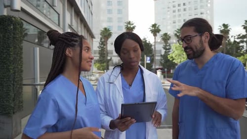 Medical Professionals Discussing a Tablet Outside Hospital Building