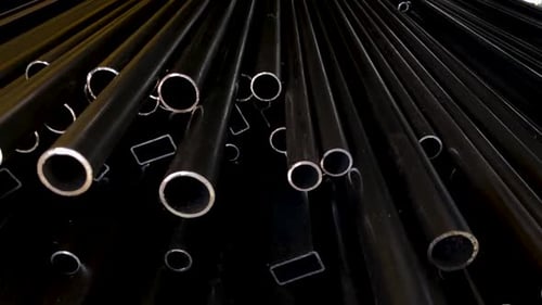 Pile of black Pipes in industrial warehouse. Black pipe on the rack