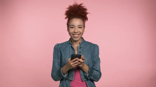 Smiling Woman With Curly Hair Looking At Phone