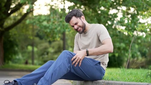 Upset athlete suffers from leg pain, calf muscle spasm during workout sitting on in an urban city