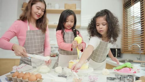 Asian attractive mother making cake with daughters in kitchen at house.