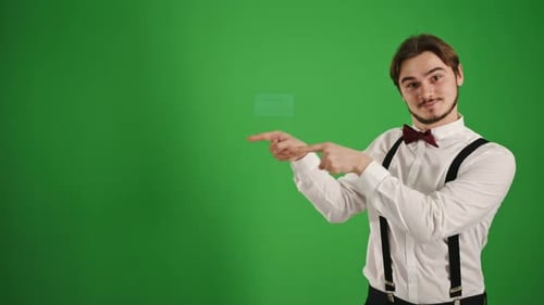 Junger Mann in formeller Kleidung zeigt für Chroma Key-Werbung nach rechts auf den grünen Bildschirm