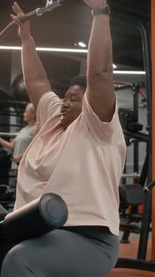 Motivated Senior Black Woman Using Lat Pulldown Machine in Gym