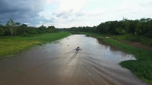 Zumbido rastreando una pequeña embarcación que navega por el río Amazonas en la selva tropical de Perú
