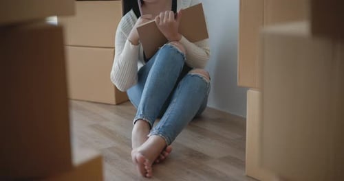 Woman Plans in New Home Surrounded by Boxes