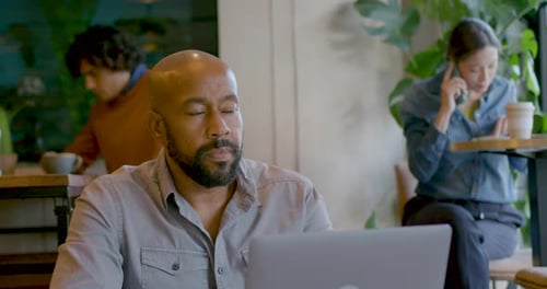 Mature Adult Businessman Contemplating and Working on Laptop in Creative Office