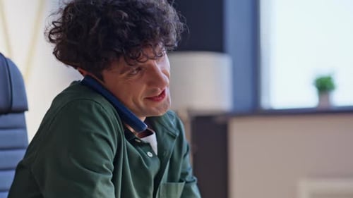Man Typing on Laptop While on Cell Phone