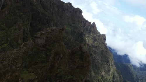 Dramatic aerial shot of rugged mountain cliffs at Pico do Arieiro in Madeira, Portugal, with clouds
