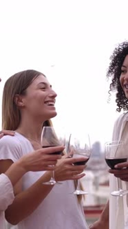 Friends Laughing Together Holding Wine on Rooftop