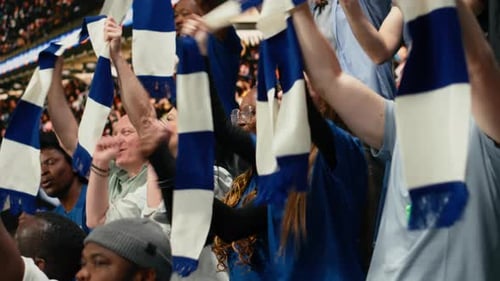 Excited Blue Team Football Supporters Raising Arms and Cheering in Stadium