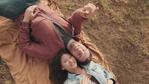 Young couple lying on blanket in the park from outside