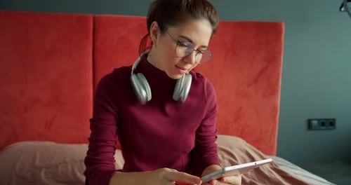 Woman On Bed Using Tablet with Headphones